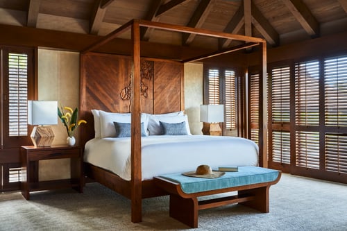 Bedroom with wooden canopy bed, ceiling fan, and open shutters.