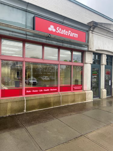 Tan and green building with red State Farm sign on front of building