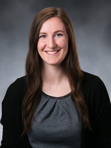 Madeleine Hermans smiles in front of a gray background