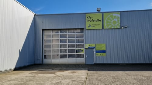 FSP-Prüfstelle mit Rolltor und Eingangstür an einem grauen Industriegebäude bei Tageslicht.