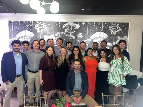 Agent Cory and his team members all dressed nicely standing next to windows indoors