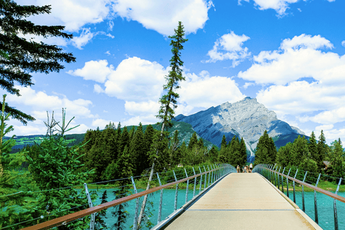 A bridge over a park that leads to a mountain.