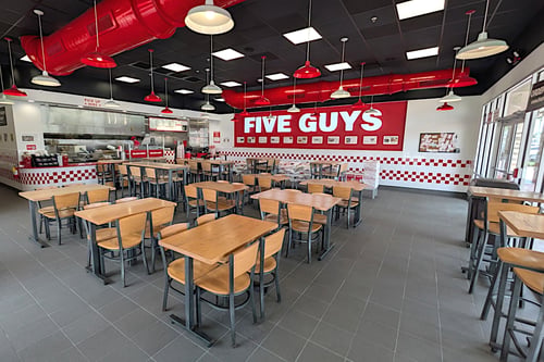 Image of the dining room of the Five Guys restaurant at 17819 Tamiami Trail  in North Port, Florida. Photo shows tables, chairs and Five Guys signage.