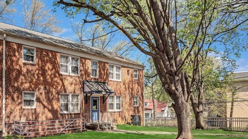 A red brick building with a tree in front at Highland Ridge Apartments, Maryland, 20743