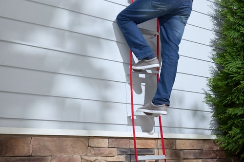 Guy using escape ladder from second story