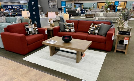Red Flexsteel sofa and oversized chair display at Slumberland Furniture Burlington, featuring modern wood coffee and end tables. Explore quality Flexsteel furniture and living room sets in Burlington, Iowa.