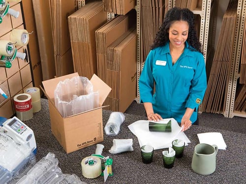 An associate packs fragile glassware for shipment from The UPS Store