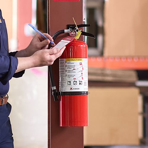 A person inspects a fire extinguisher