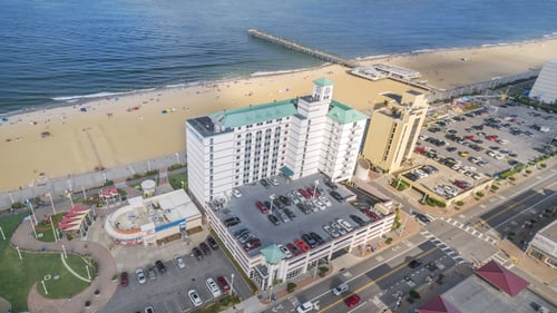 An aerial view of Boardwalk Resort and Villas. Virginia Beach is located directly behind the resort, and the pier lies nearby.