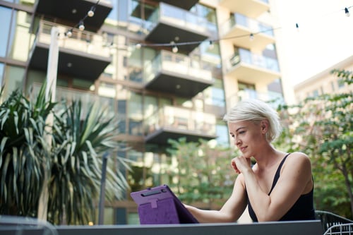 Woman sitting outside at a table on a tablet