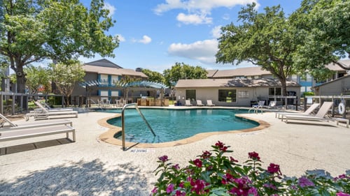 a pool with lounge chairs and trees in the background  at Vesper, Texas