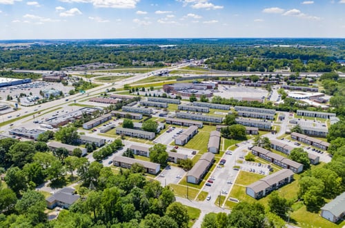 Aerial drone shot of The Park at Greenhill apartments in West Indianapolis, showing buildings, green lawns, and nearby highway access.