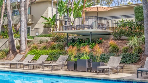 A pool surrounded by chairs and trees at West Park Village, Los Angeles, CA