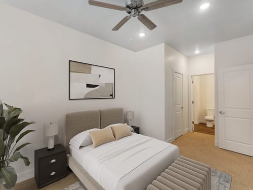 A white bedroom with a bed, a ceiling fan, and two ceiling lights at Atlas Apartments in Idaho Falls, ID