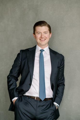 Cole Heideman, Investment Advisor, wearing a suit and tie, and leaning against a wall