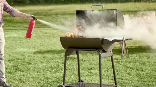 person extinguishing a grill fire outdoors