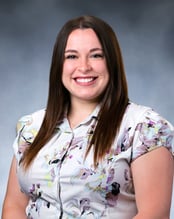 Delaney Pease, MS smiling in front of a dark gray background.