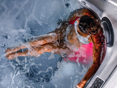 Jacuzzi® J508™ luxury hot tub with bubbling hydrotherapy jets with a woman relaxing in the water