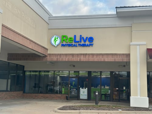 “Exterior of ReLive Physical Therapy clinic in a shopping center with blue and green signage and large front windows.”