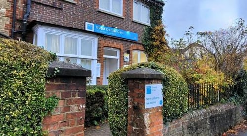Bupa Dental Care Guildford is in a red brick building with black iron railings, trees, bushes and greenery