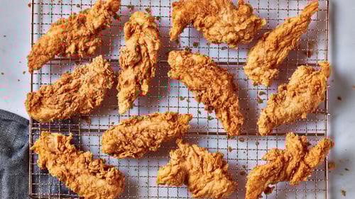 Assorted pieces of golden fried chicken on a cooling rack