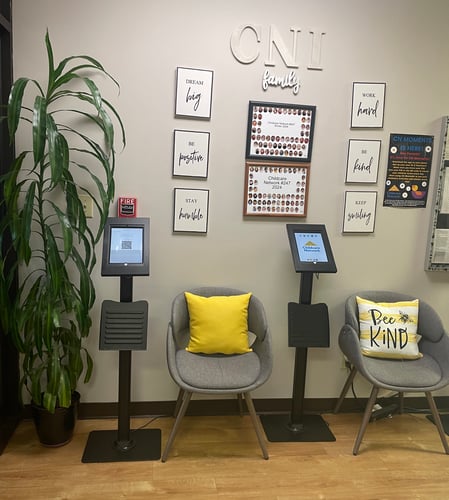 Bright and welcoming lobby with chairs for parents and a colorful bulletin board displaying cute moments from the daycare.