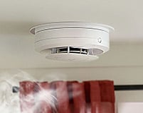 Smoke rises towards a smoke alarm.