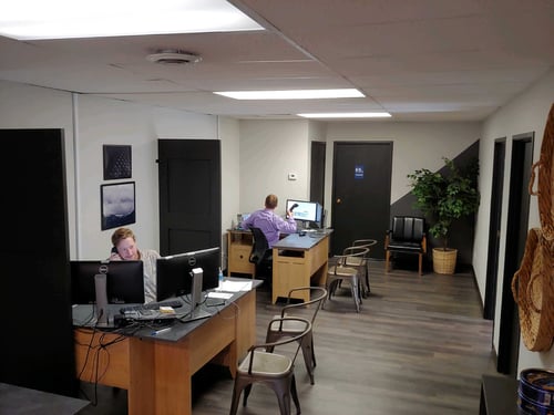 White walls with gray flooring and tan desks with black doors