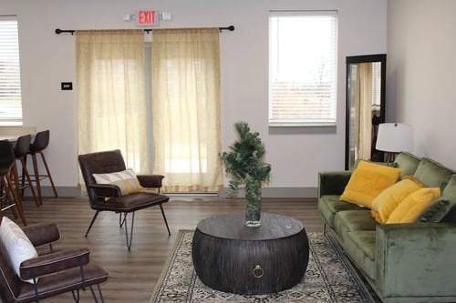 Community Lounge with green couch and chairs at The 2525 Apartments in Warsaw