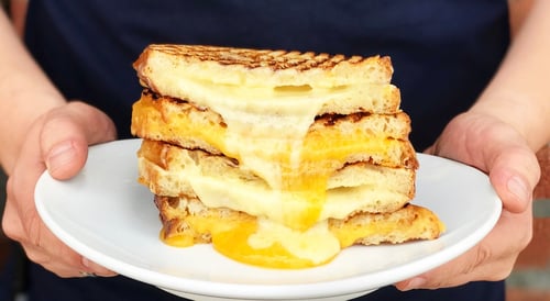 A stack of grilled cheese sandwiches on a white plate