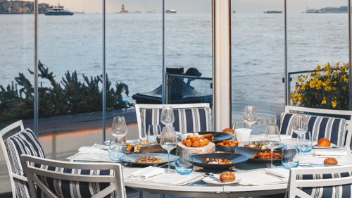 A table with a beautiful selection of foods overlooking a river.