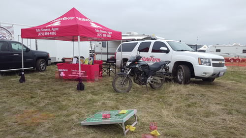 Red and white State Farm tent with white car