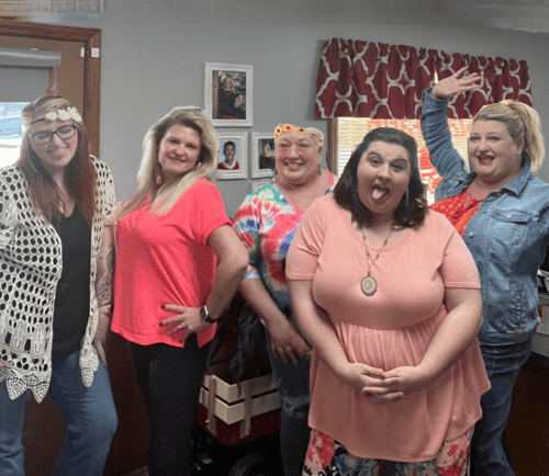 Kristina and four team members smiling together in office