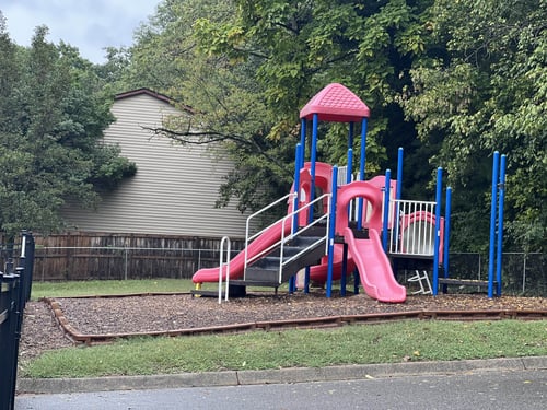 View of an empty playground featuring slides, climbing structures, and open space for play.