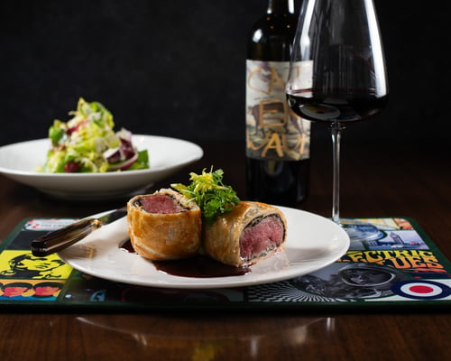 Beef Wellington with potato purée, herb salad, and red wine demi