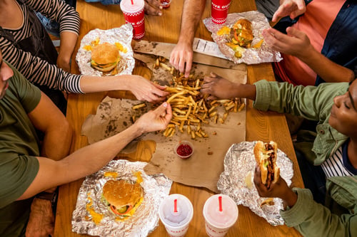 A top-down photograph of a group of friends having a meal at a Five Guys restaurant.