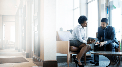 two professional people viewing a tablet in a modern office space