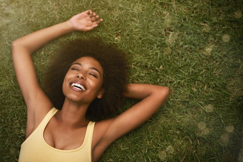 person laying on the grass with teeth shining