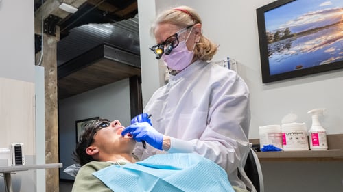 A man in a dental chair at Gentle Dental Ashland, with a female dentist working on a teeth cleaning.