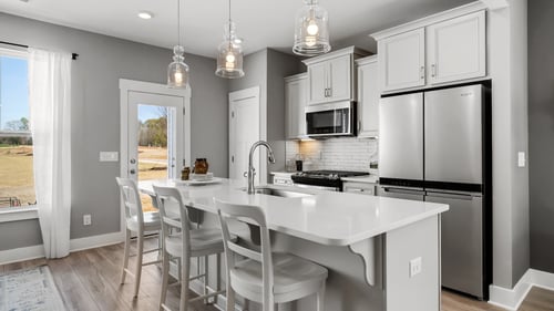 Kitchen with white cabinets, stainless steel appliances and large island in the Litchfield Home Plan at DRB Hickory Heights community