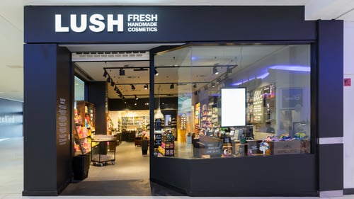 Lush Portsmouth's store front inside Cascades Shopping Centre. Through the window you can see various bright and colourful cosmetics products and gift sets.