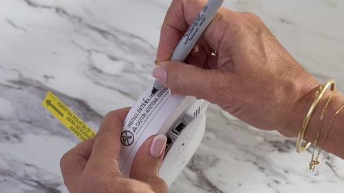 woman making note of the date of installation of a safety device