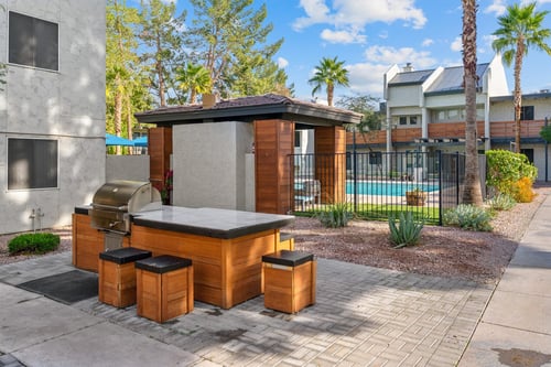 Barbecue station beside the swimming pool at Sono Tempe Apartments with grills and bar seating.