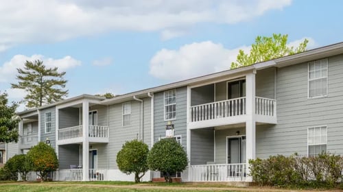gray apartment building with trees and bushes lining the ground