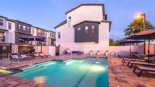 A pool with a lounge area at twilight at Dolce Villagio Townhomes