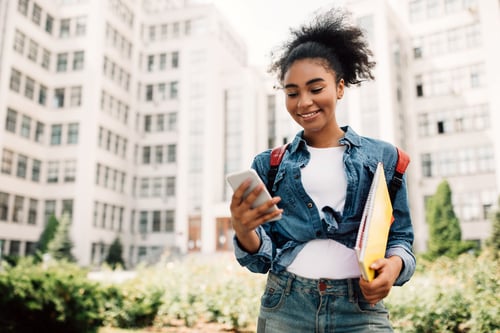 Woman standing near buildings looking at phone