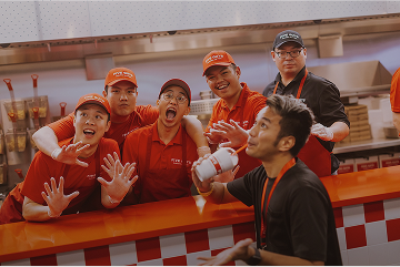 Group of restaurant employees in red uniforms with the text Our Crew. Our Family.
