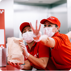 A collection of red uniformed restaurant crew members working and smiling.