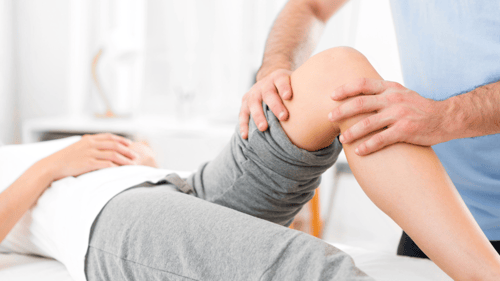 therapist working on a patients knee during a physical therapy session