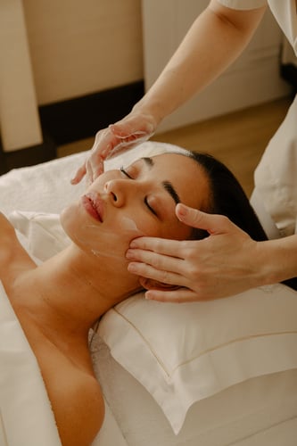 Close-up of a woman enjoying a soothing facial massage in a tranquil spa environment.